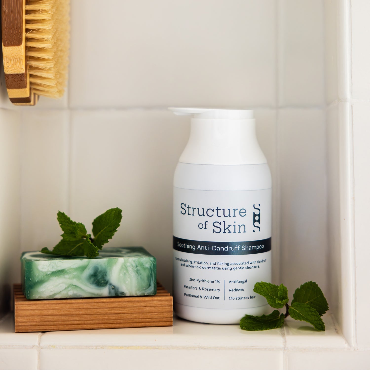 Bottle of Structure of Skin dandruff shampoo on a bathroom shelf with a soap and mint leaves.